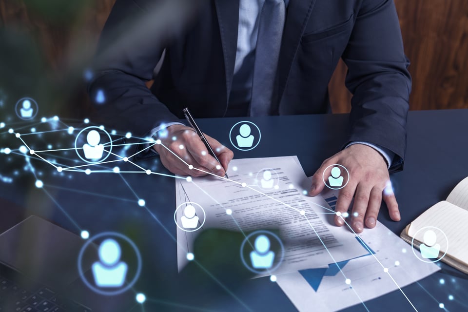 Procurement manager sits at his desk signing telecom contract, overlaid with digital icons representing telecom connections