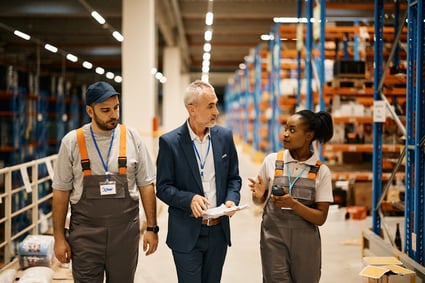 Corporate executive speaks with two of the company’s MRO managers as they walk through supply warehouse.