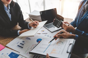 Corporate team calculates potential cost savings after reviewing procurement spend analysis.